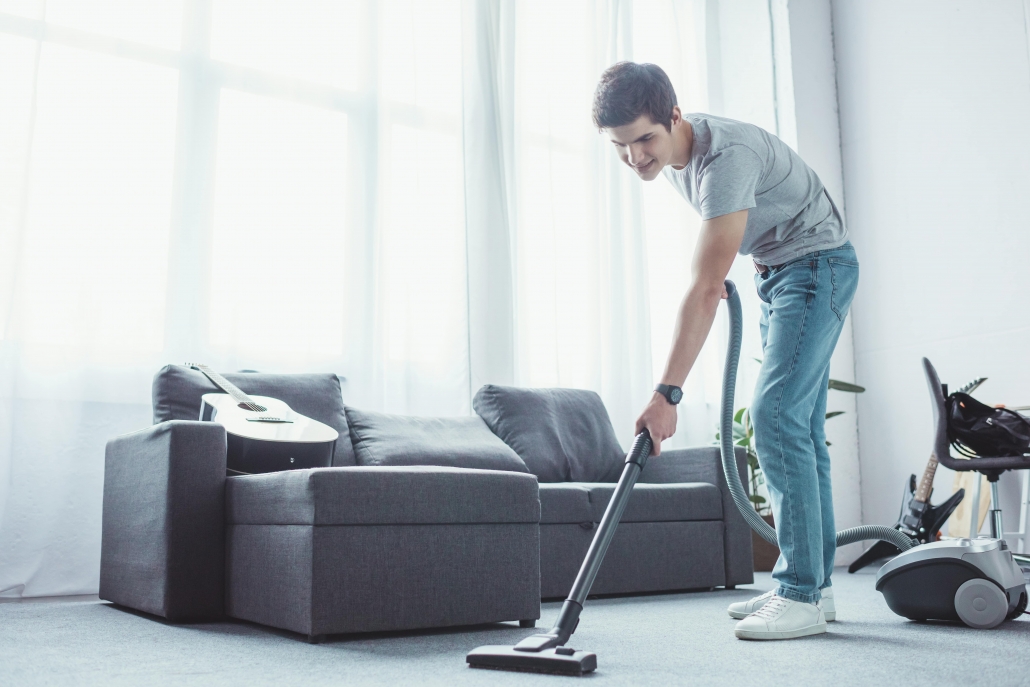 teenager vacuuming floor in living room with a vacuum